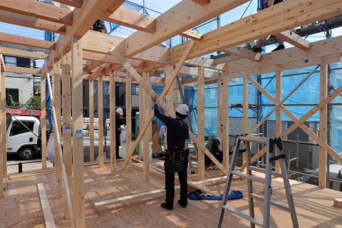 木造住宅の骨組みの中の大工の後ろ姿(イメージ)