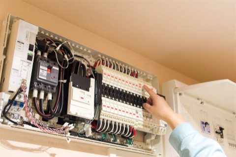住宅の分電盤のブレーカーを確かめる手元(イメージ)
