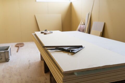 部屋に積み重ねた石膏ボードと大工の道具（イメージ）