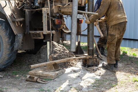 掘削の機械の横で管をつなぐ作業員（イメージ）