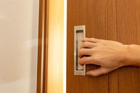 木目の引き戸の取っ手に手をかけたところ(イメージ)