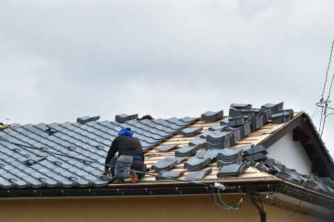瓦屋根の葺き替えをする職人の後ろ姿(イメージ)