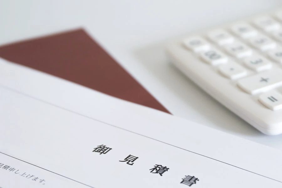 机の上の御見積書と電卓。金額を出している場面