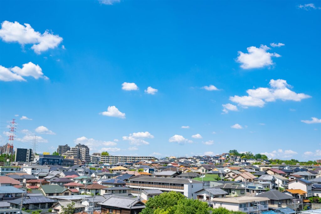 青空の下に、戸建ての家がすき間なく並ぶ住宅地を高い所から見た眺め