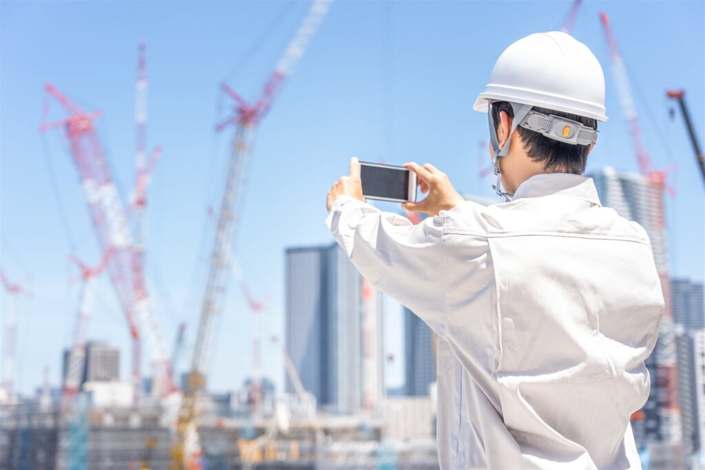 ヘルメットをかぶった人がスマートフォンで撮る後ろ姿